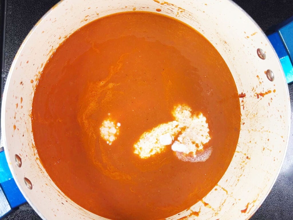 Adding the cream to the pureed tomato basil soup mixture.