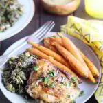 Single air fryer lemon pepper chicken thigh on a plate with collard greens and roasted carrots.