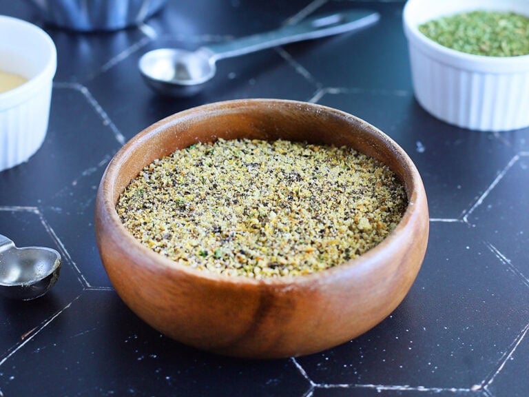 Dish of homemade lemon pepper seasoning with small dishes of various herbs and spices in the background.