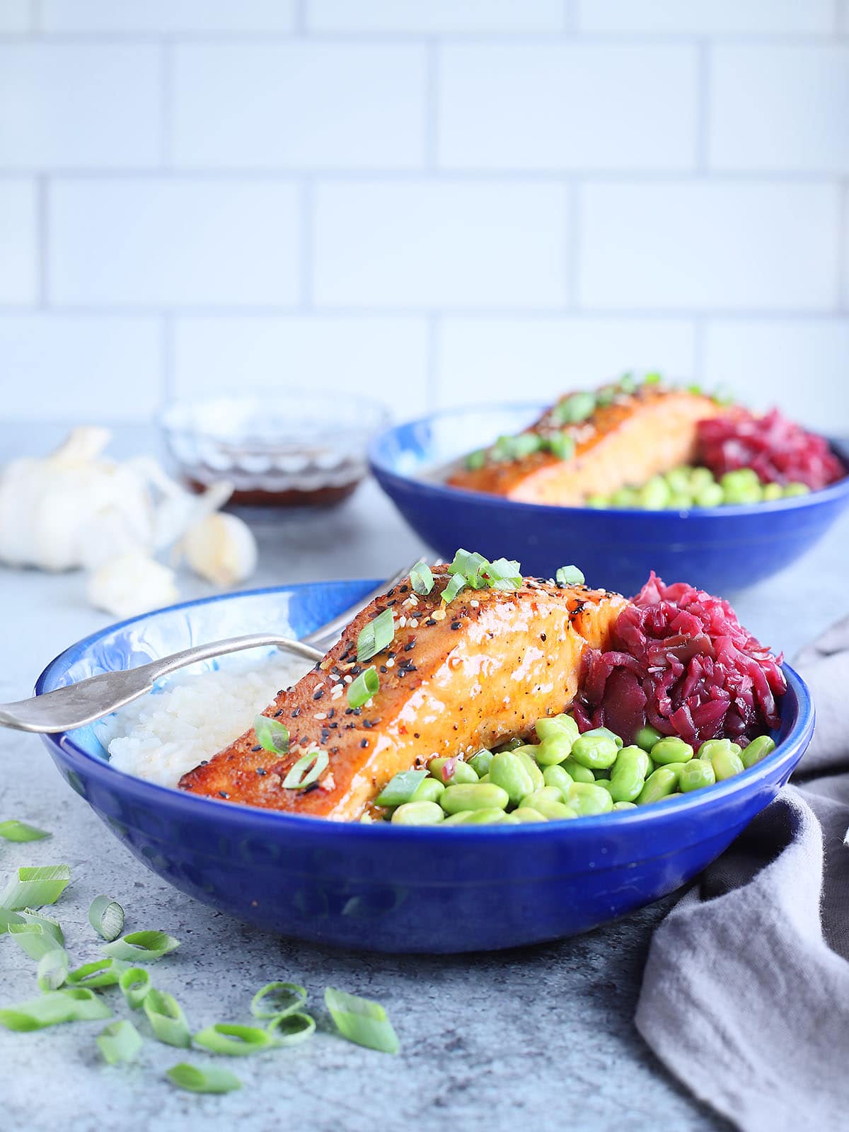 Filet of air fryer teriyaki salmon in a bowl with white rice, shelled edamame and pickled cabbage.