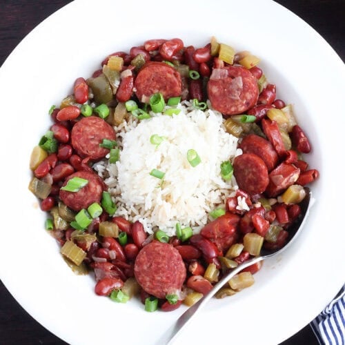 Spoon tucked into a serving of Instant Pot red beans and rice garnished with sliced green onions.