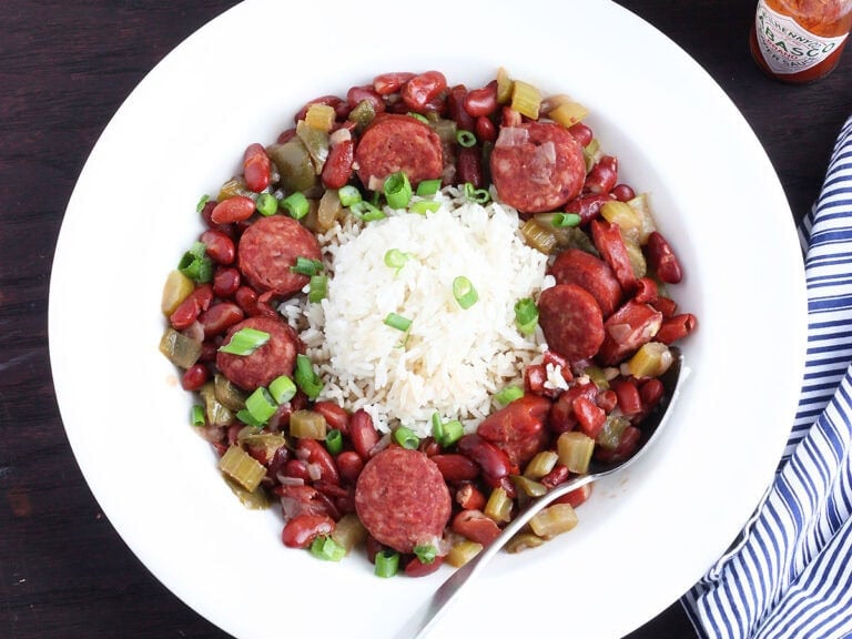 Spoon tucked into a serving of Instant Pot red beans and rice garnished with sliced green onions.