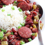 Spoon tucked into a serving of Instant Pot red beans and rice garnished with sliced green onions.