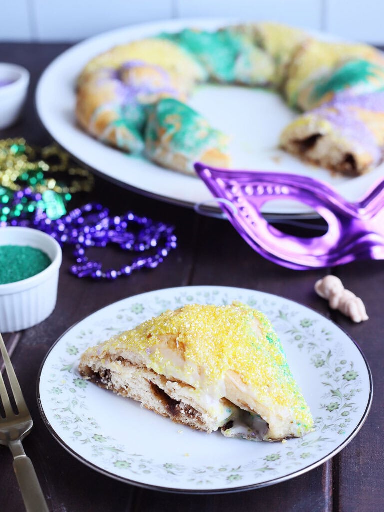 Single slice of king cake on a plate decorated with flowers.