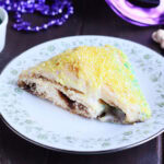 Single slice of king cake on a plate decorated with flowers.