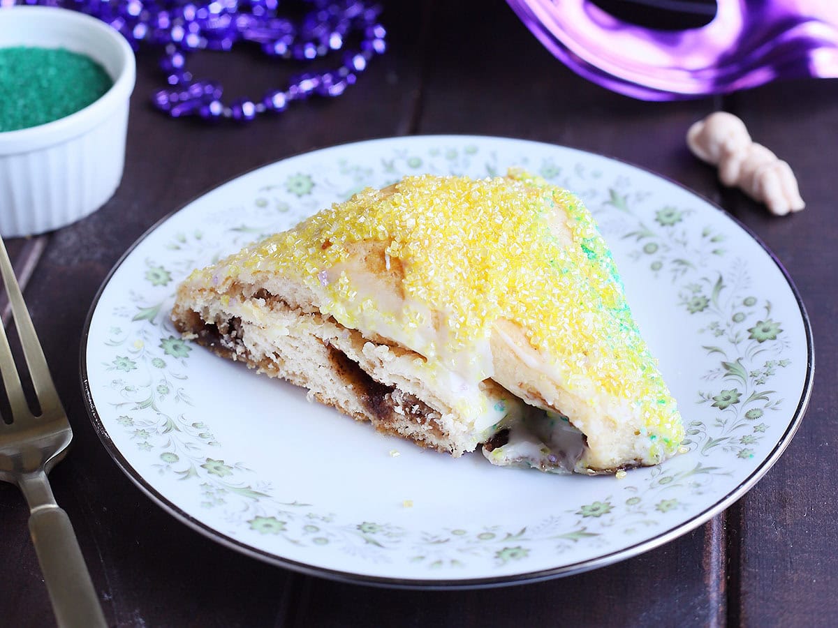 Single slice of king cake on a plate decorated with flowers.