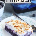 One slice of blueberry jello salad on a floral plate with a spoon.