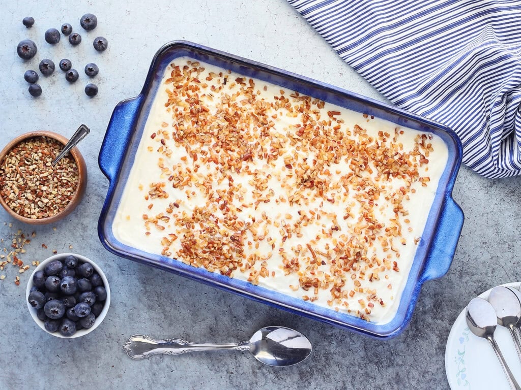 Serving dish of blueberry jello salad with a small bowl of fresh blueberries and chopped pecans on the side.