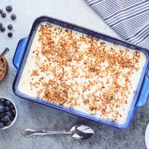 Serving dish of blueberry jello salad with a small bowl of fresh blueberries and chopped pecans on the side.