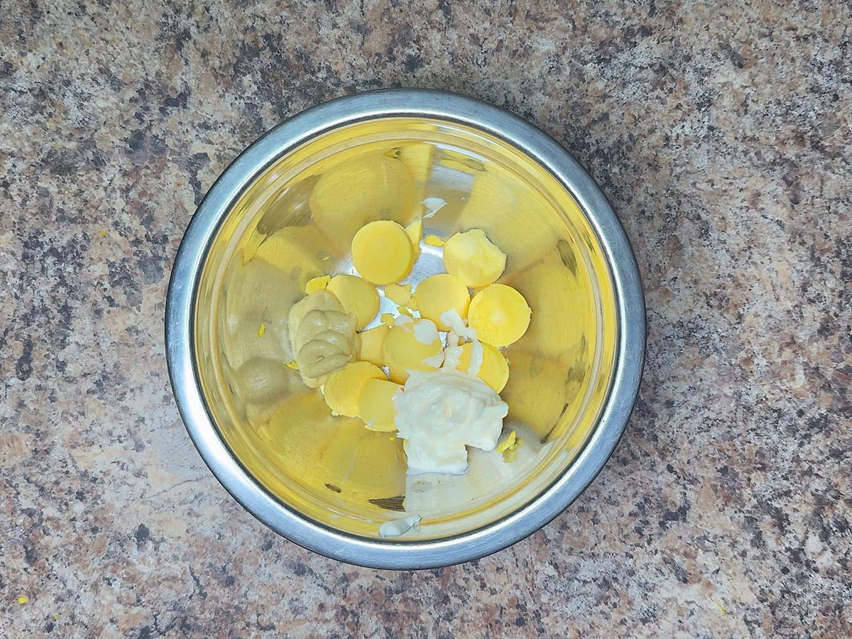 Egg yolks, mayonnaise, and Dijon mustard in a medium mixing bowl.