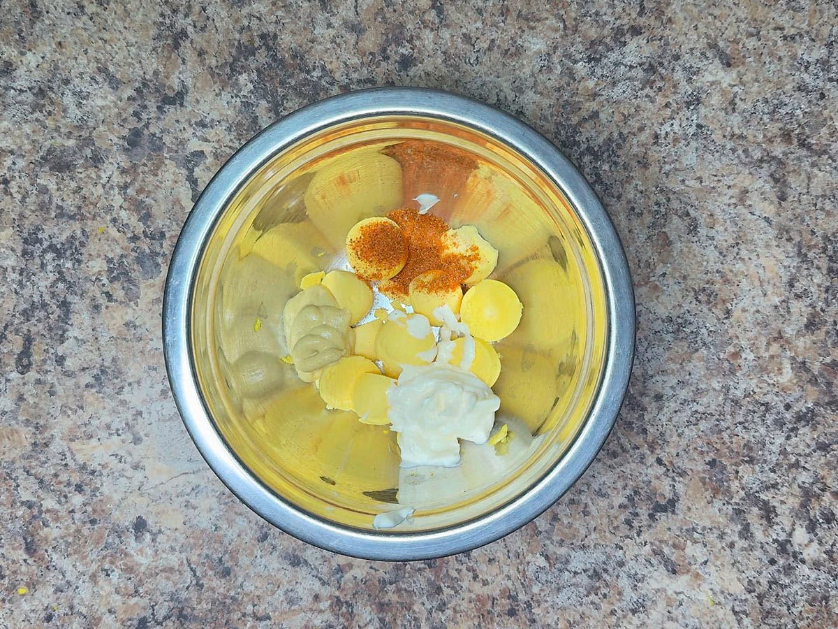 Egg yolks, mayonnaise, Dijon mustard, and Old Bay seasoning in a medium mixing bowl.