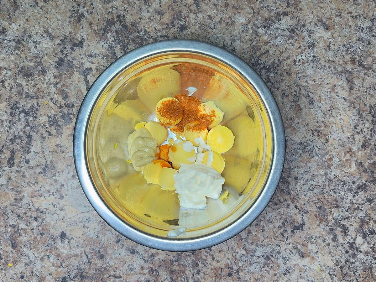 Egg yolks, mayonnaise, Dijon mustard, Old Bay seasoning, and hot sauce in a medium mixing bowl.