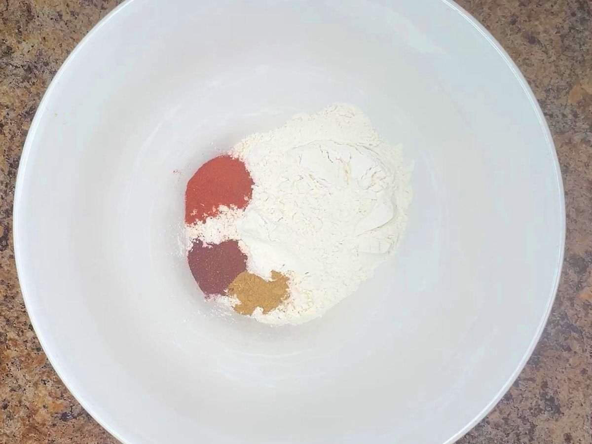 Flour, paprika, chili powder, cumin, and salt in a mixing bowl.