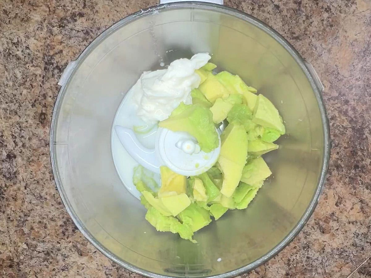 Diced avocado, sour cream and buttermilk in the bowl of a food processor.