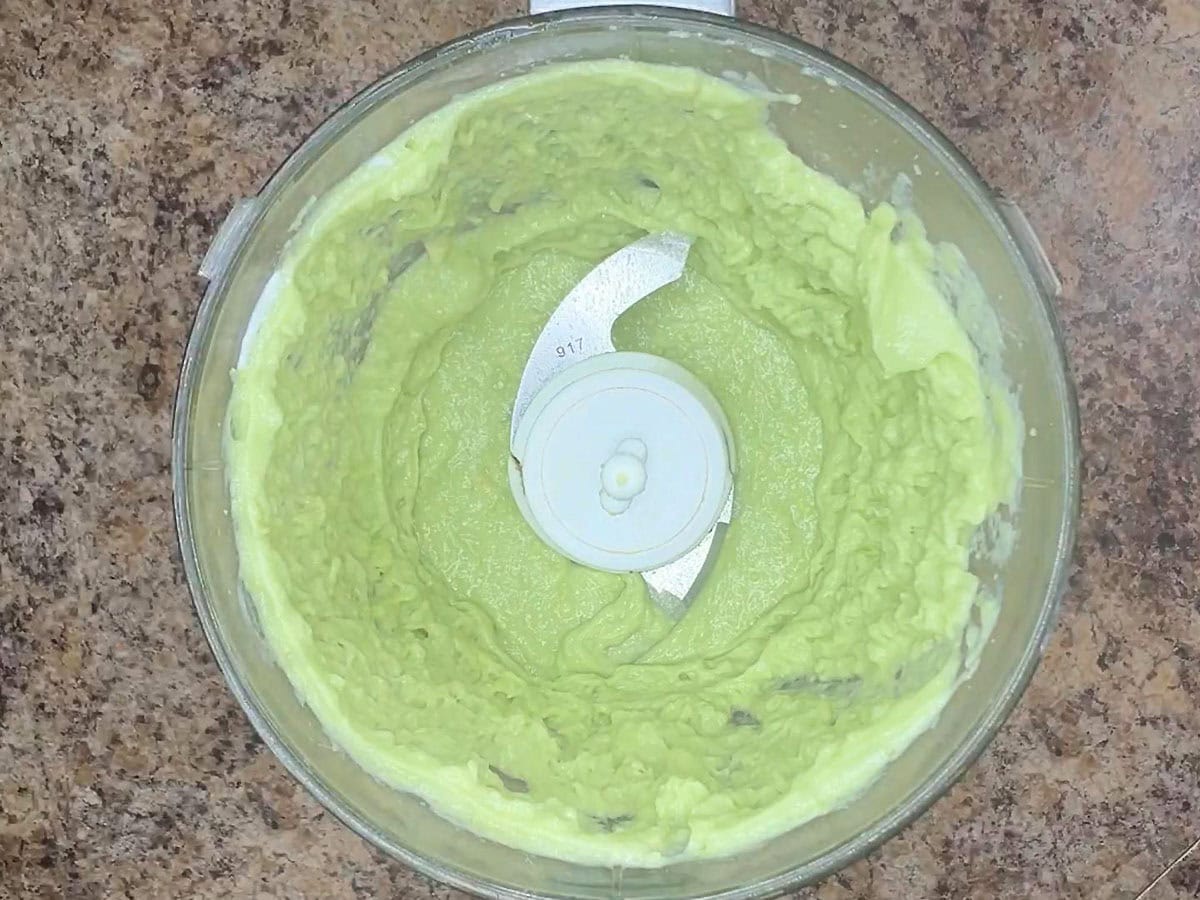 Avocado crema ingredients processed until smooth in the bowl of a food processor.