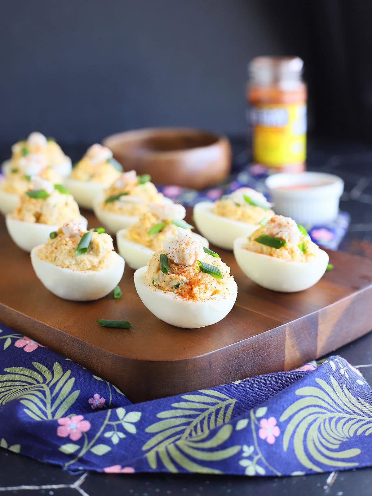 Crab deviled eggs garnished with crab meat, paprika and fresh chives on a wooden cutting board.