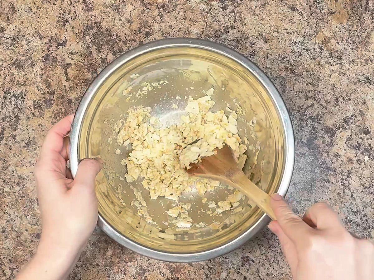Stirring the crushed crackers until they absorb the juice from the can of salmon.