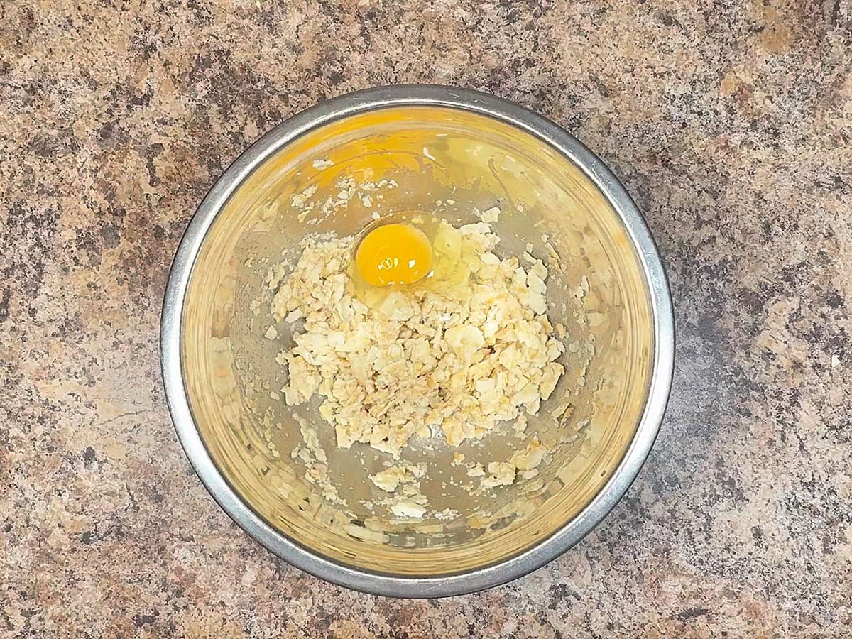 One large egg added to the crushed crackers in a large mixing bowl.