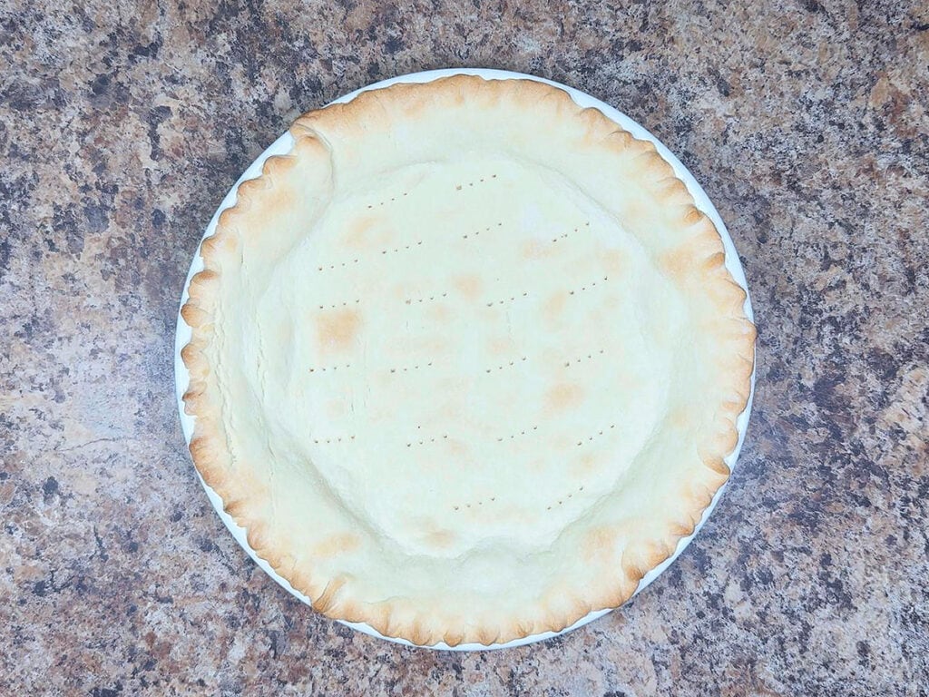 Prebaked pie crust cooling on a counter.