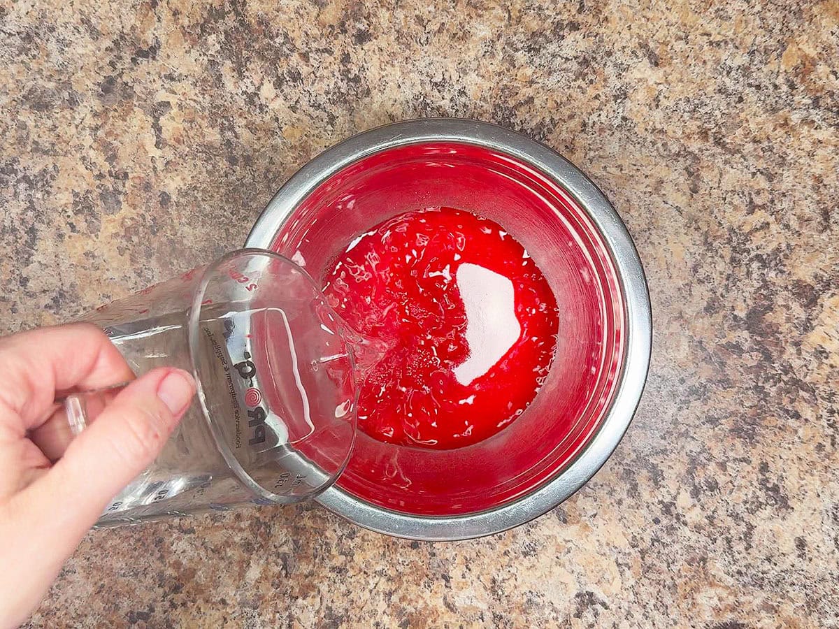 Adding hot water to the strawberry gelatin.