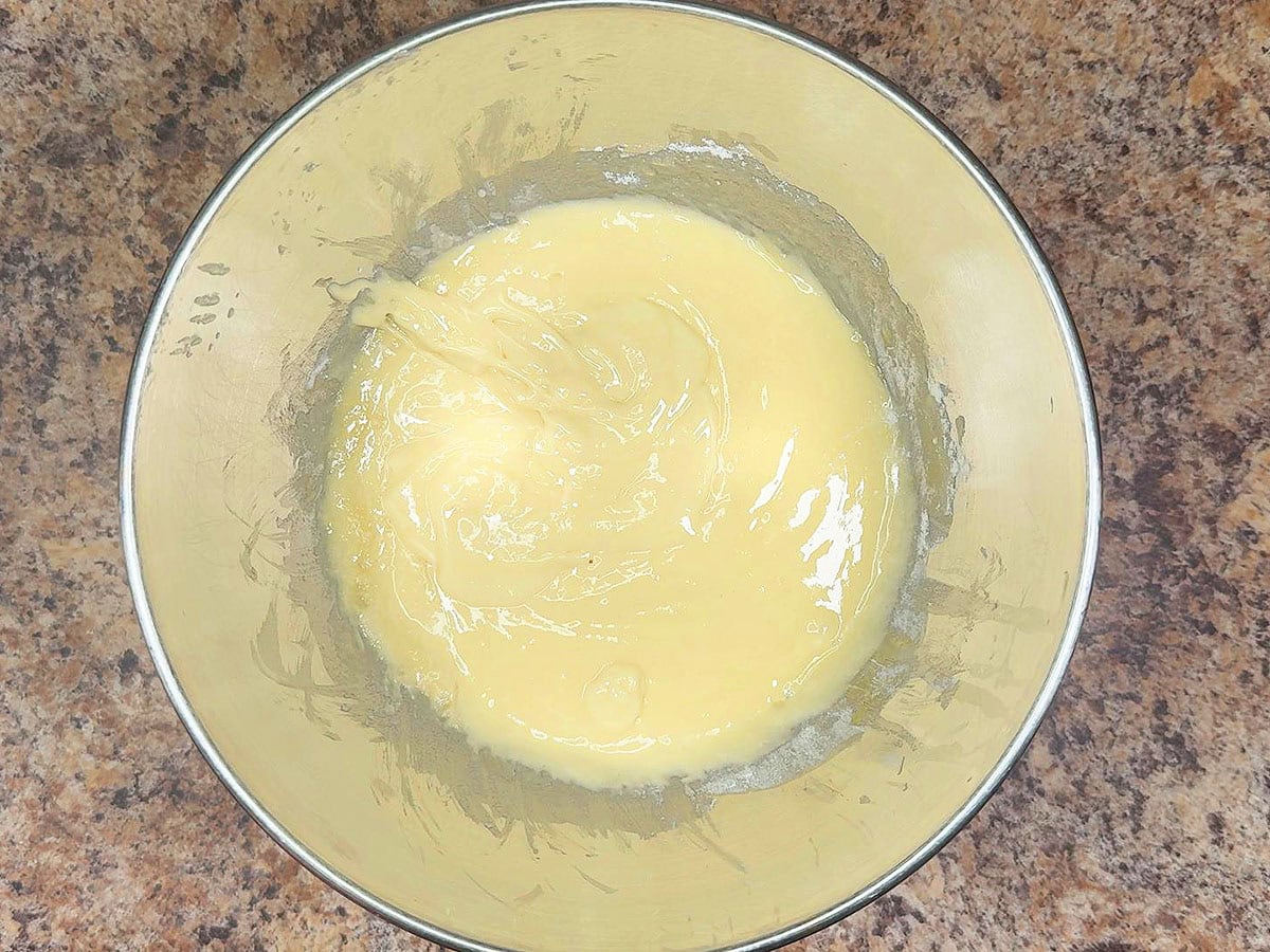 Mixed white cake batter in a large mixing bowl.