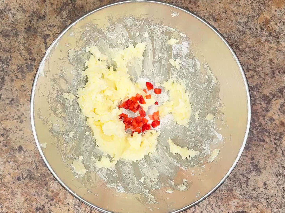 Adding the first tablespoon of diced strawberries to the buttercream icing.