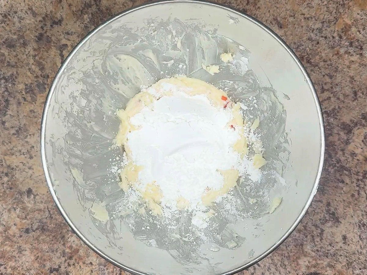 Adding the second cup of powdered sugar to the strawberry buttercream frosting.