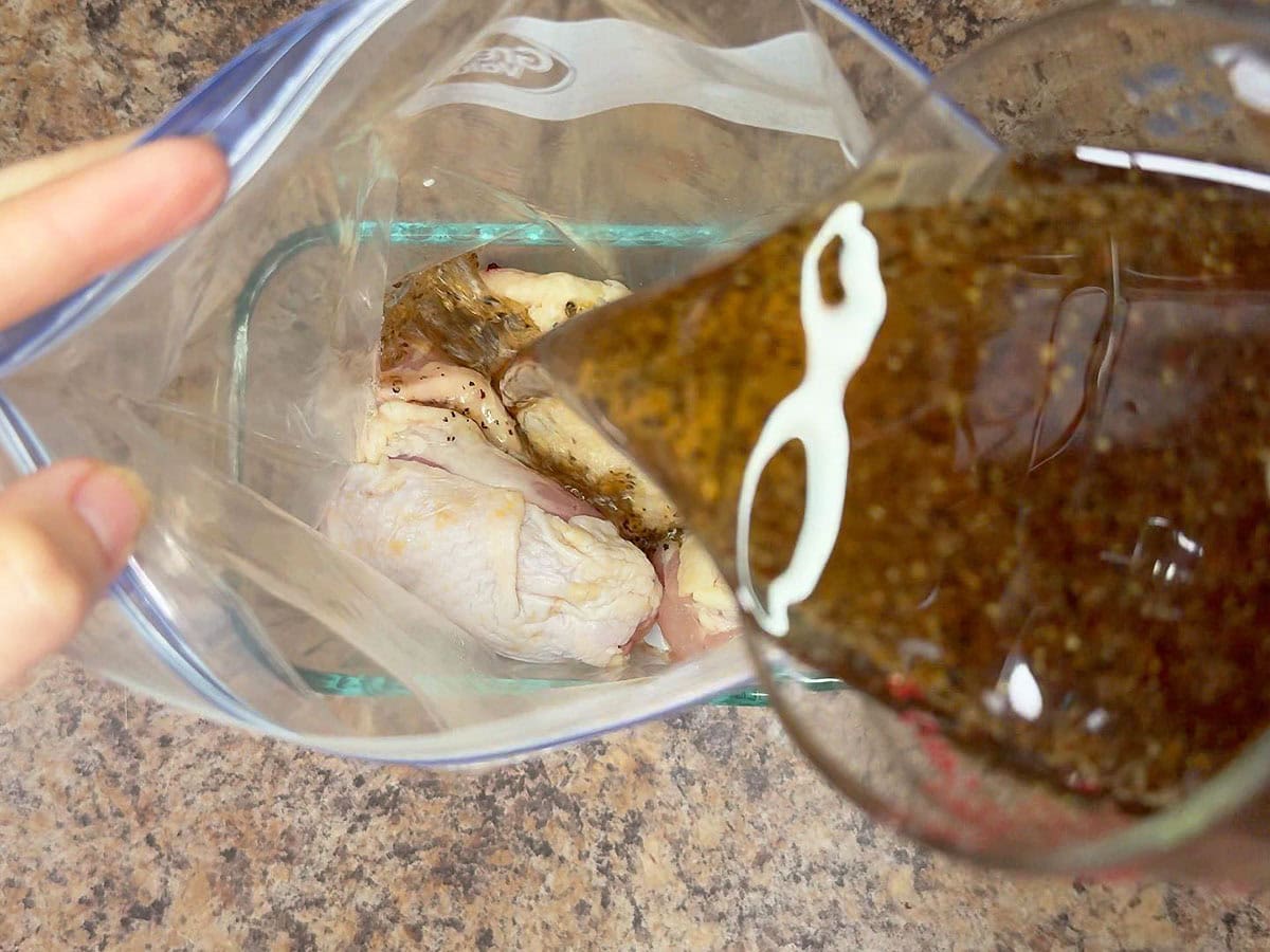 Pouring the apple cider vinegar chicken marinade over chicken thighs in a plastic freezer bag.