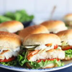 Platter of catfish sliders garnished with coleslaw and sauce.