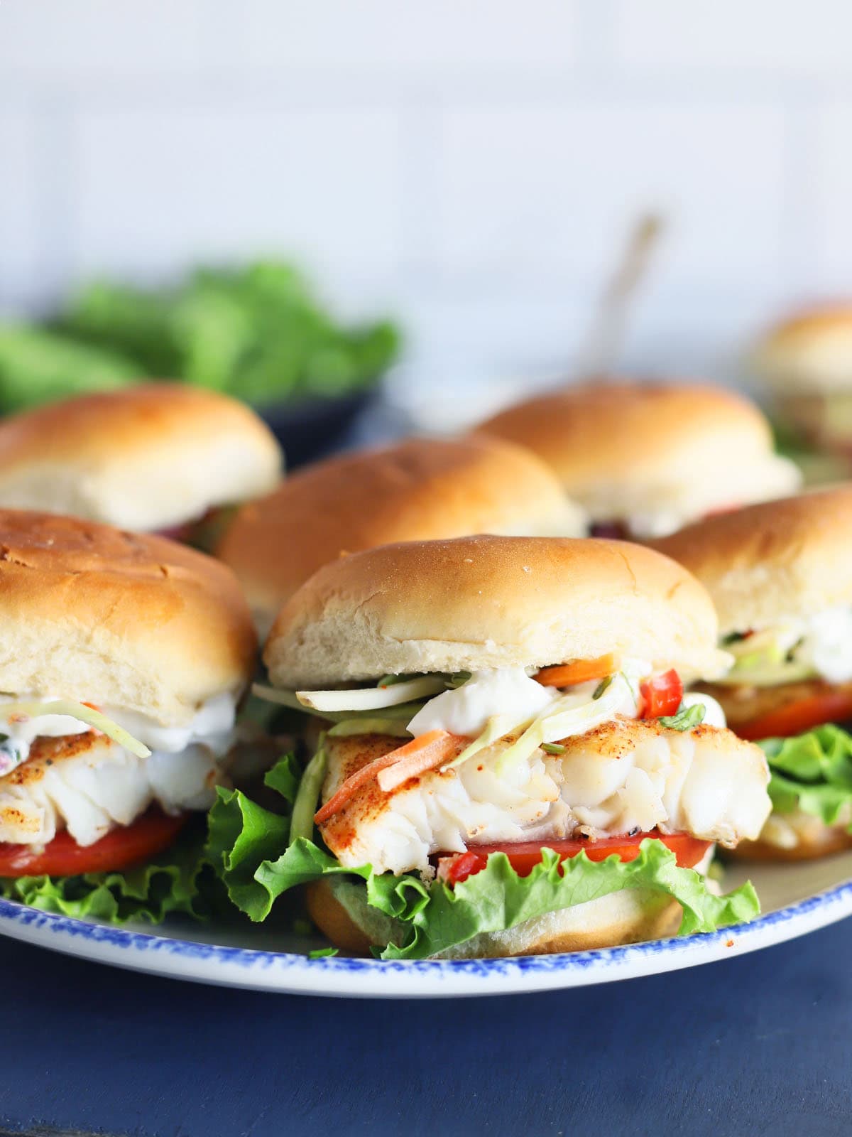 Platter of catfish sliders garnished with coleslaw and sauce.