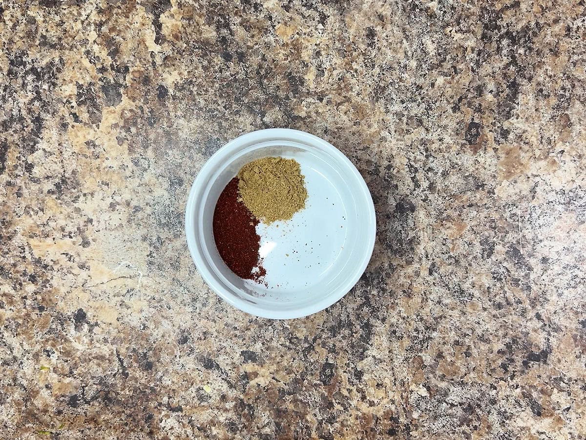 Chili powder and cumin in a small bowl.