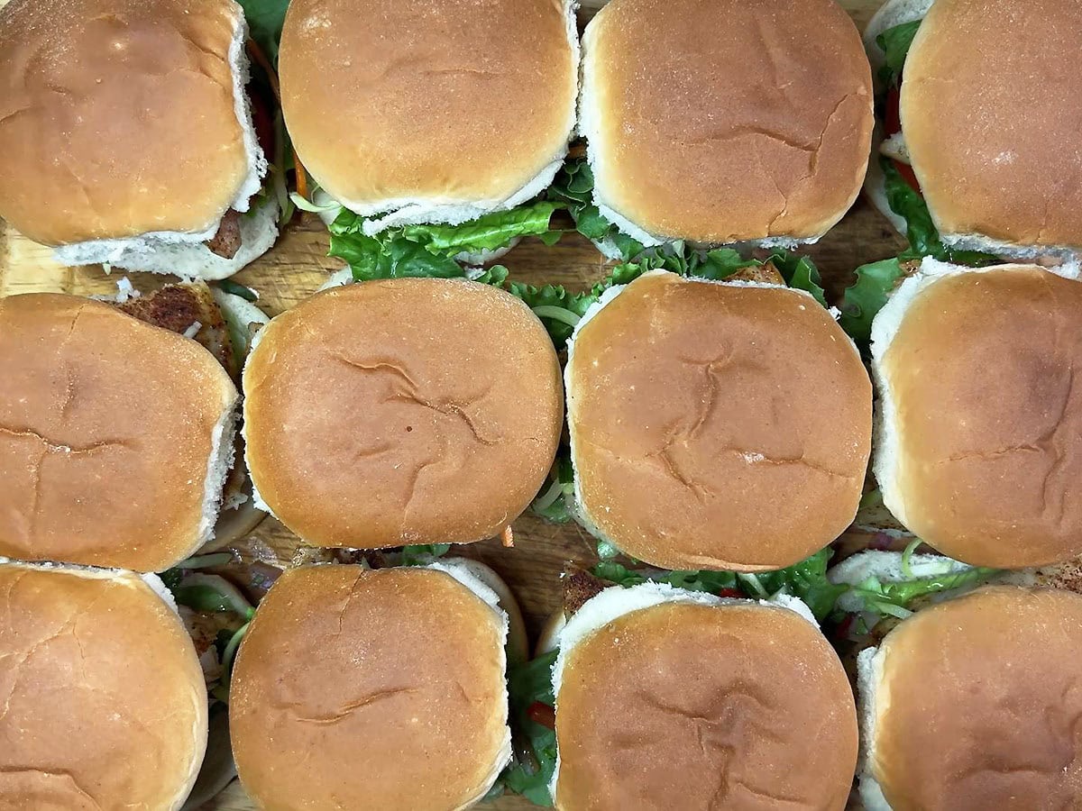 Assembled sliders on a wooden cutting board topped with a bun.