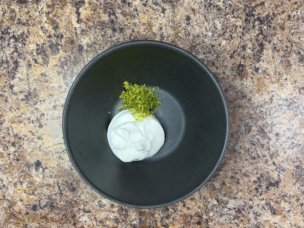 Sour cream and zested lime peel in a small mixing bowl.