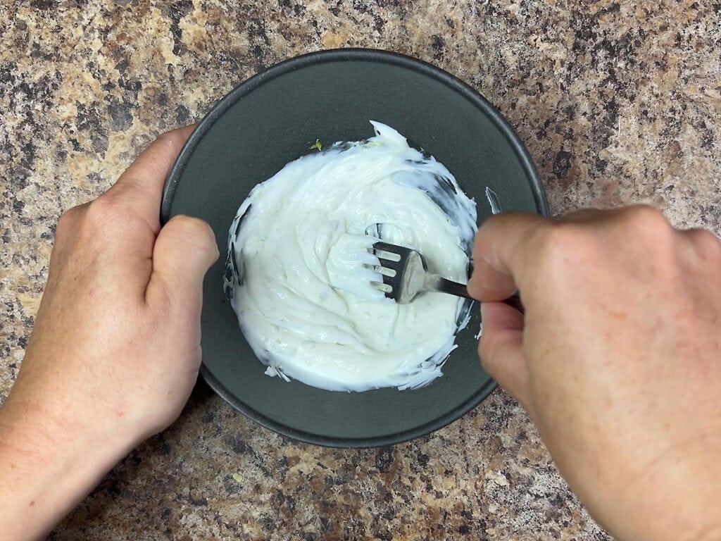Hands mixing together the ingredients for the creamy lime sauce.