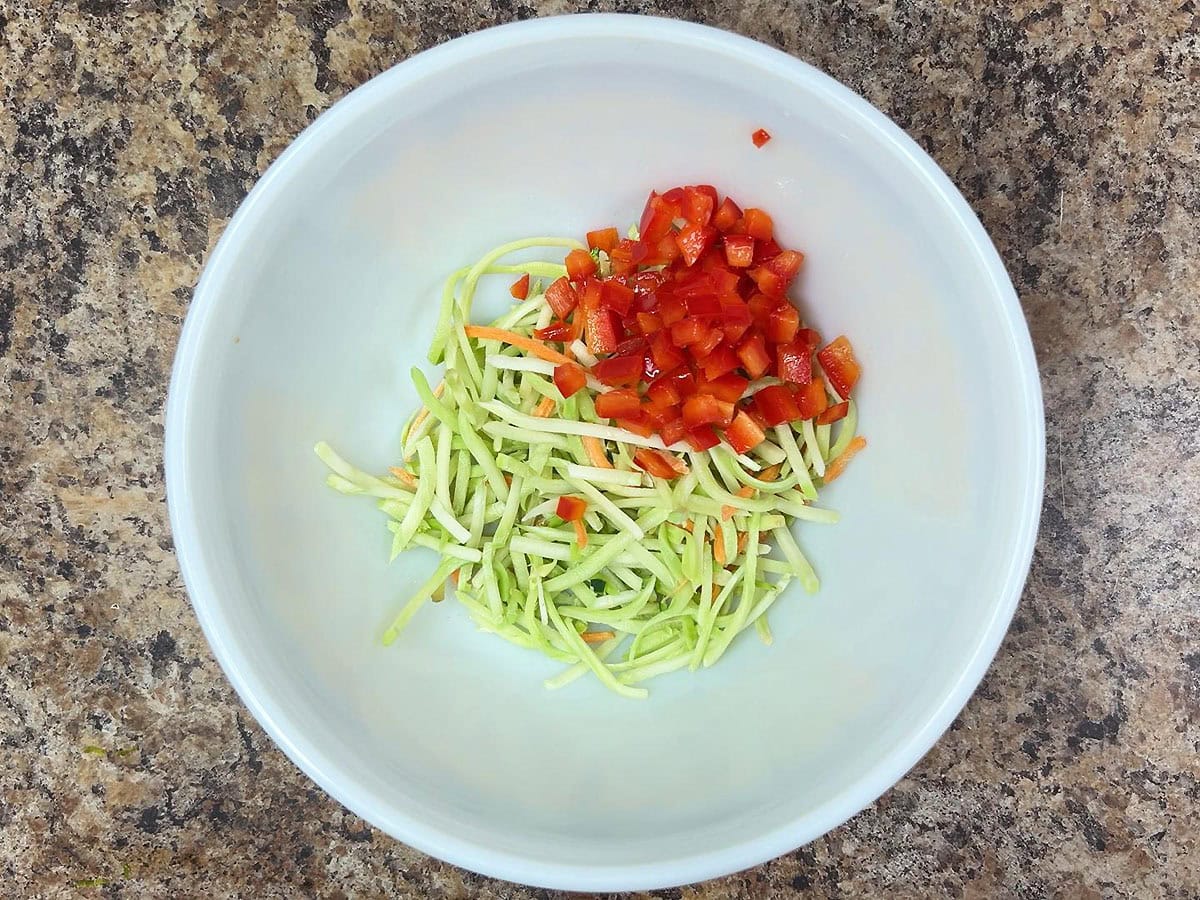 Coleslaw mix and diced red bell pepper in a mixing bowl.