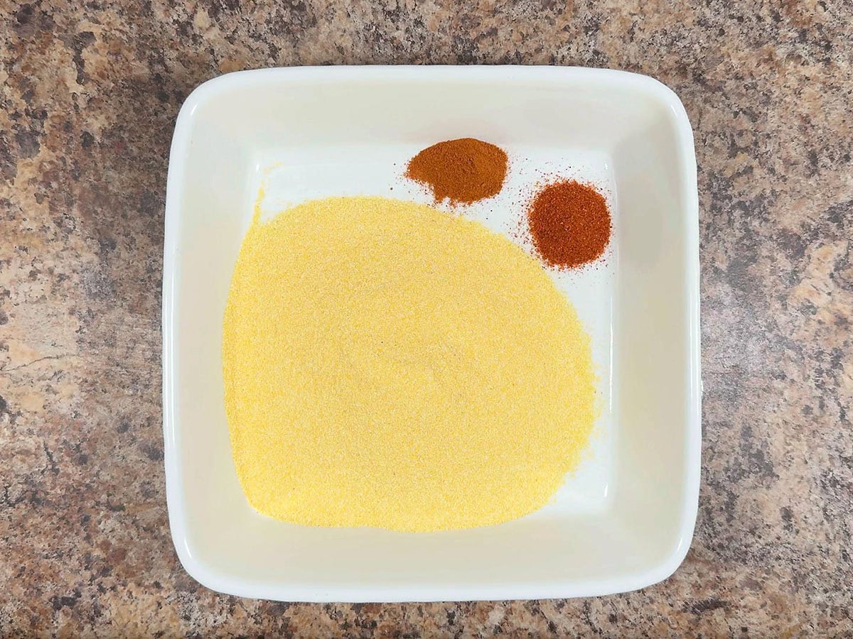Cornmeal, cayenne, and paprika in a shallow dish.