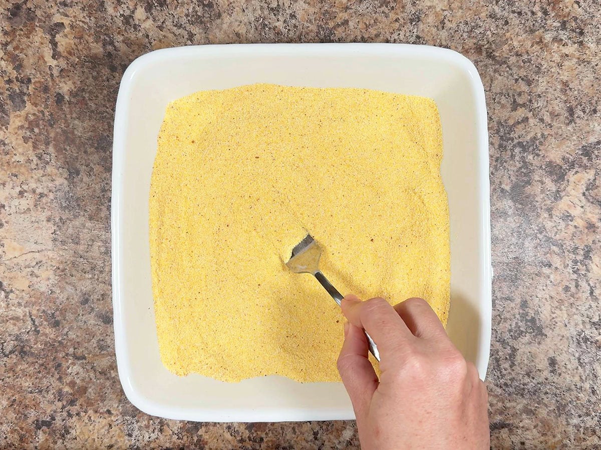 Mixing together cornmeal, cayenne, and paprika in a shallow dish.