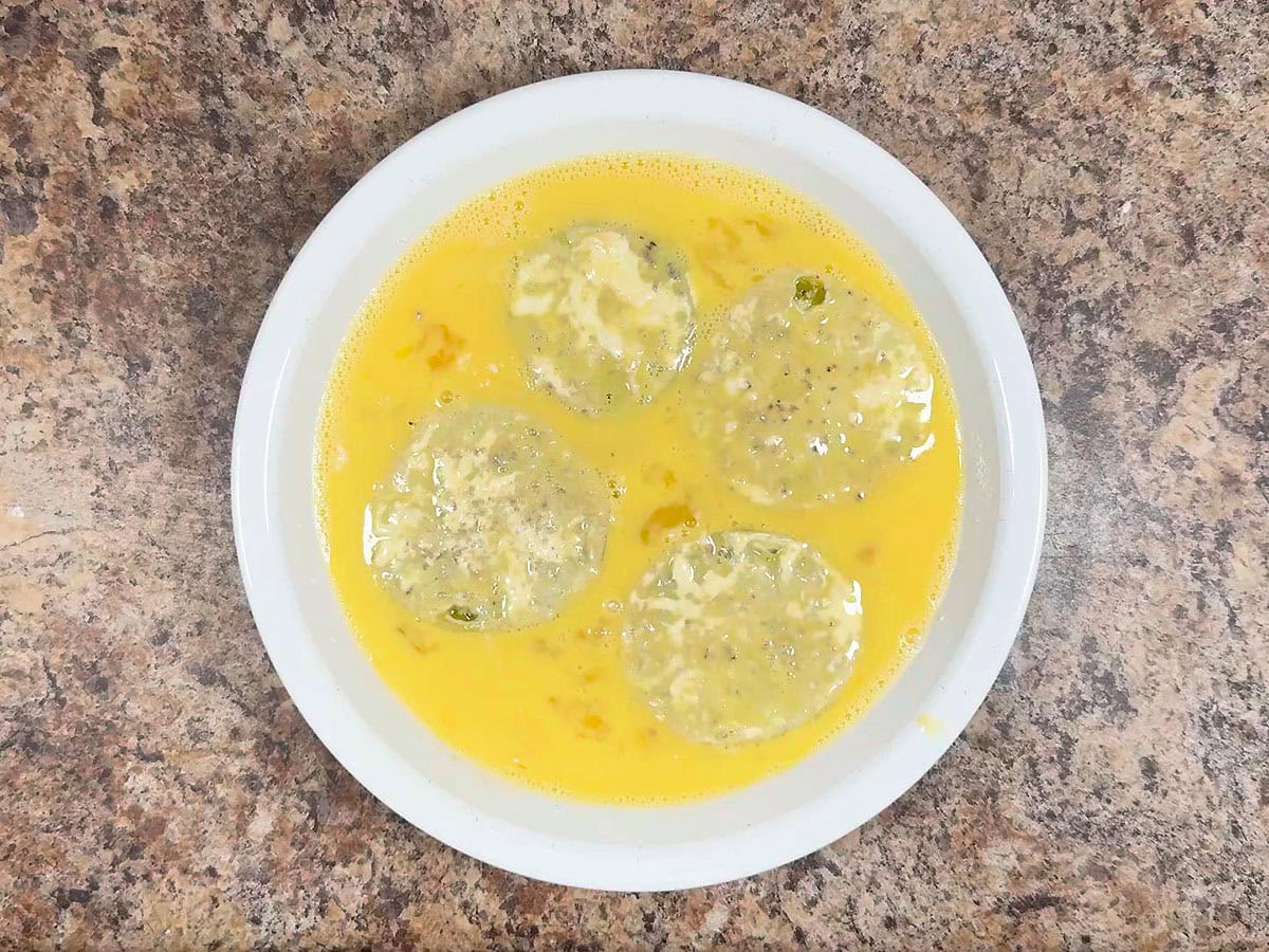 Coating both sides of sliced green tomatoes in eggs and milk.