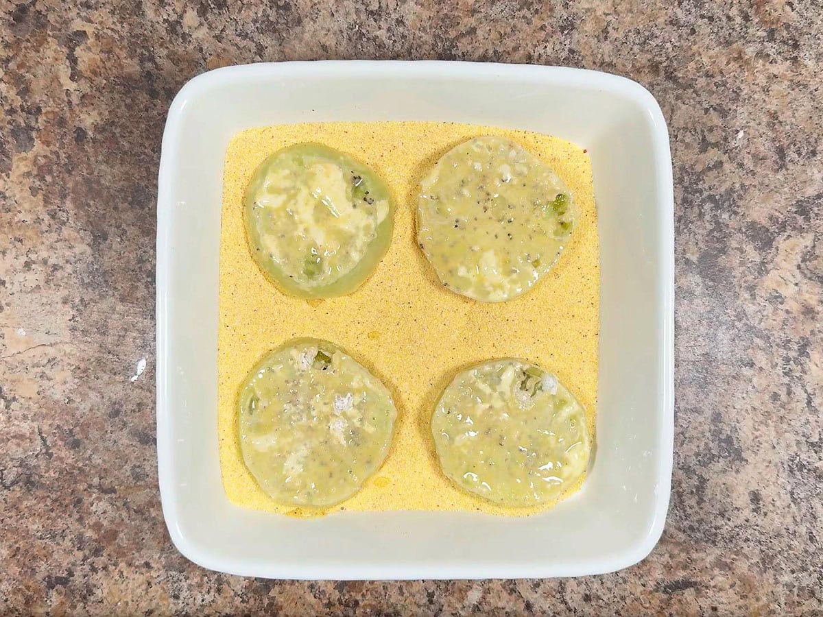 Coating sliced green tomatoes in cornmeal.