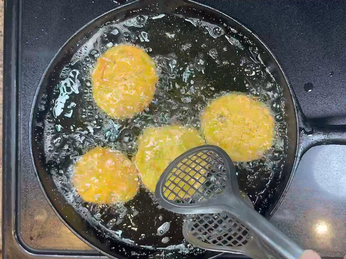 Flipping the fried green tomatoes halfway through the cooking time.