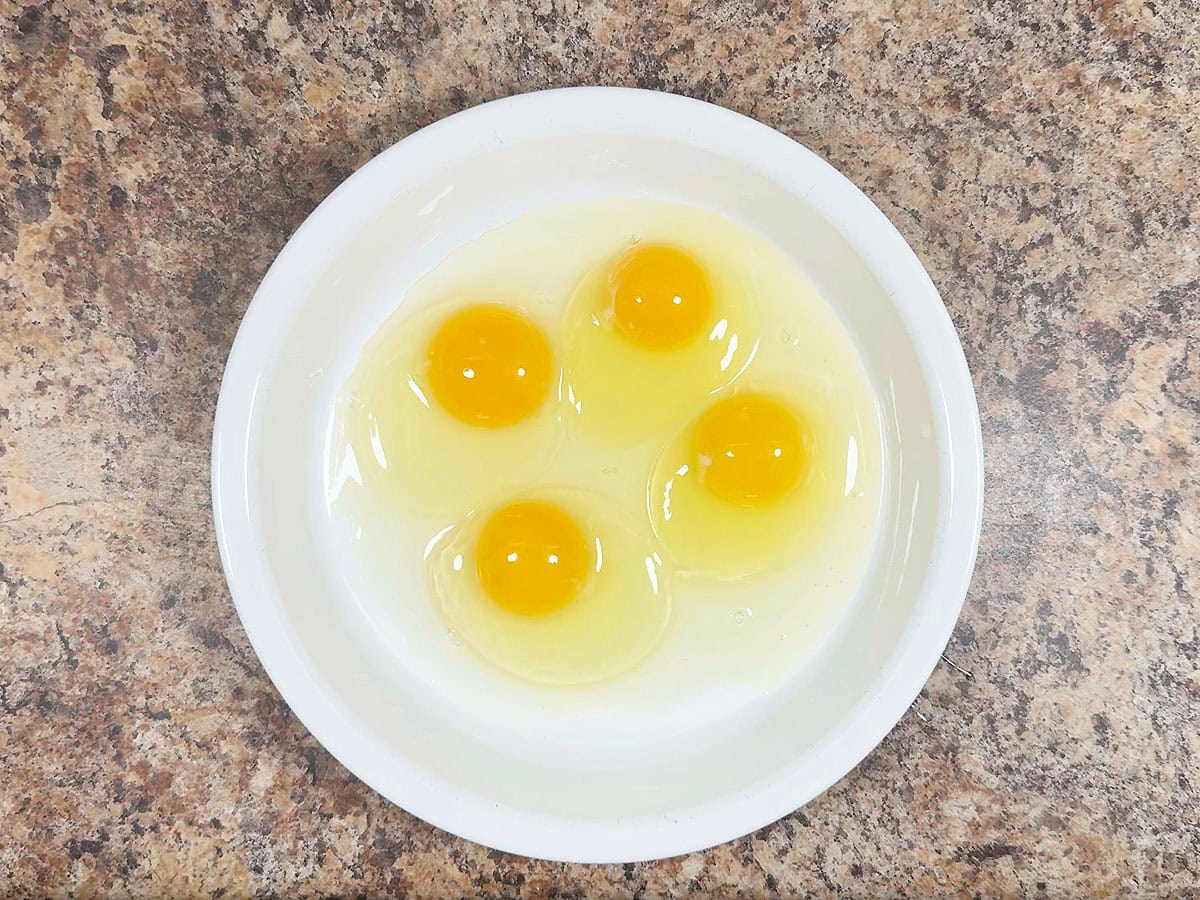 Four whole eggs in a shallow dish.