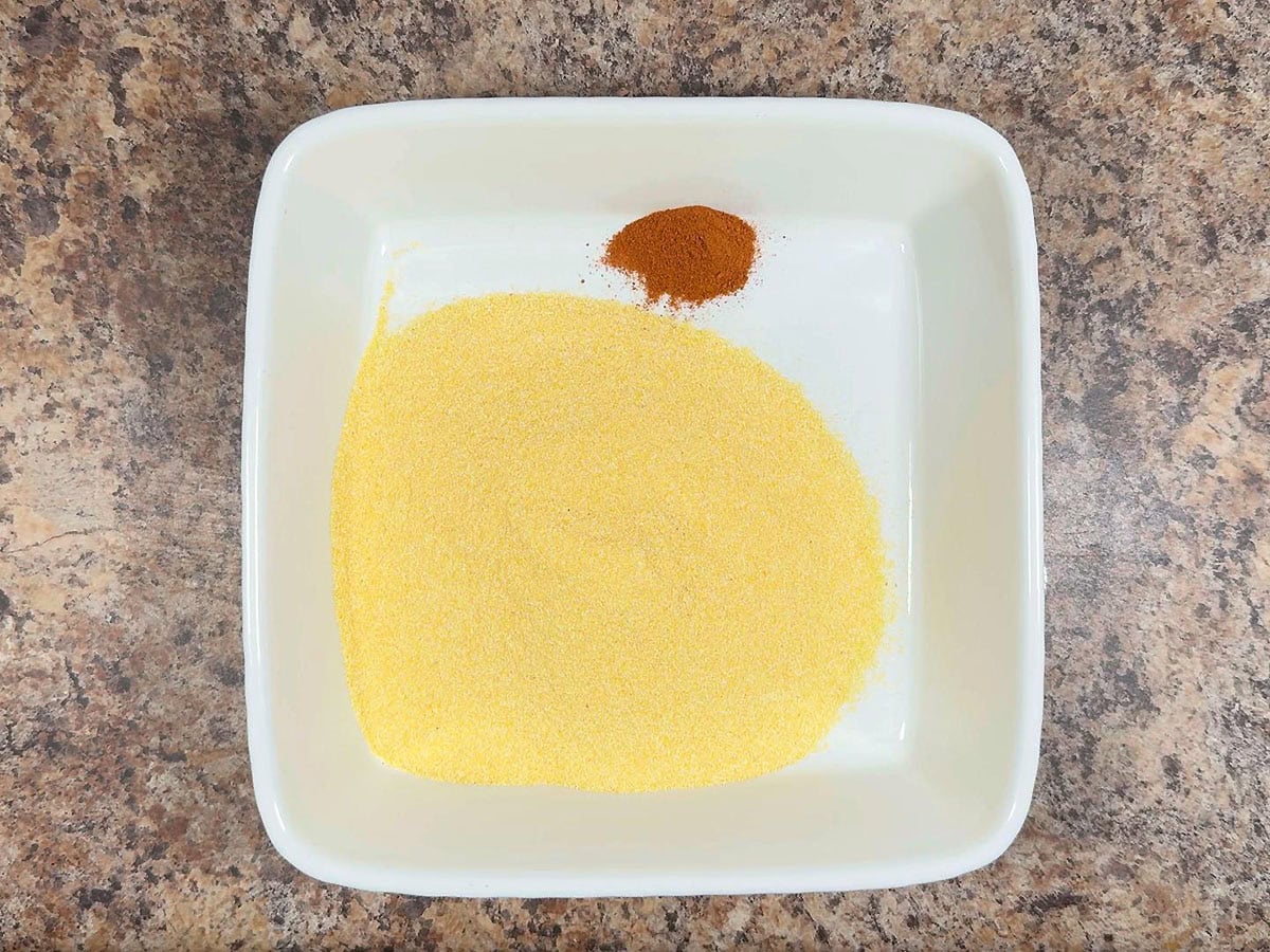 Cornmeal and paprika in a shallow dish.