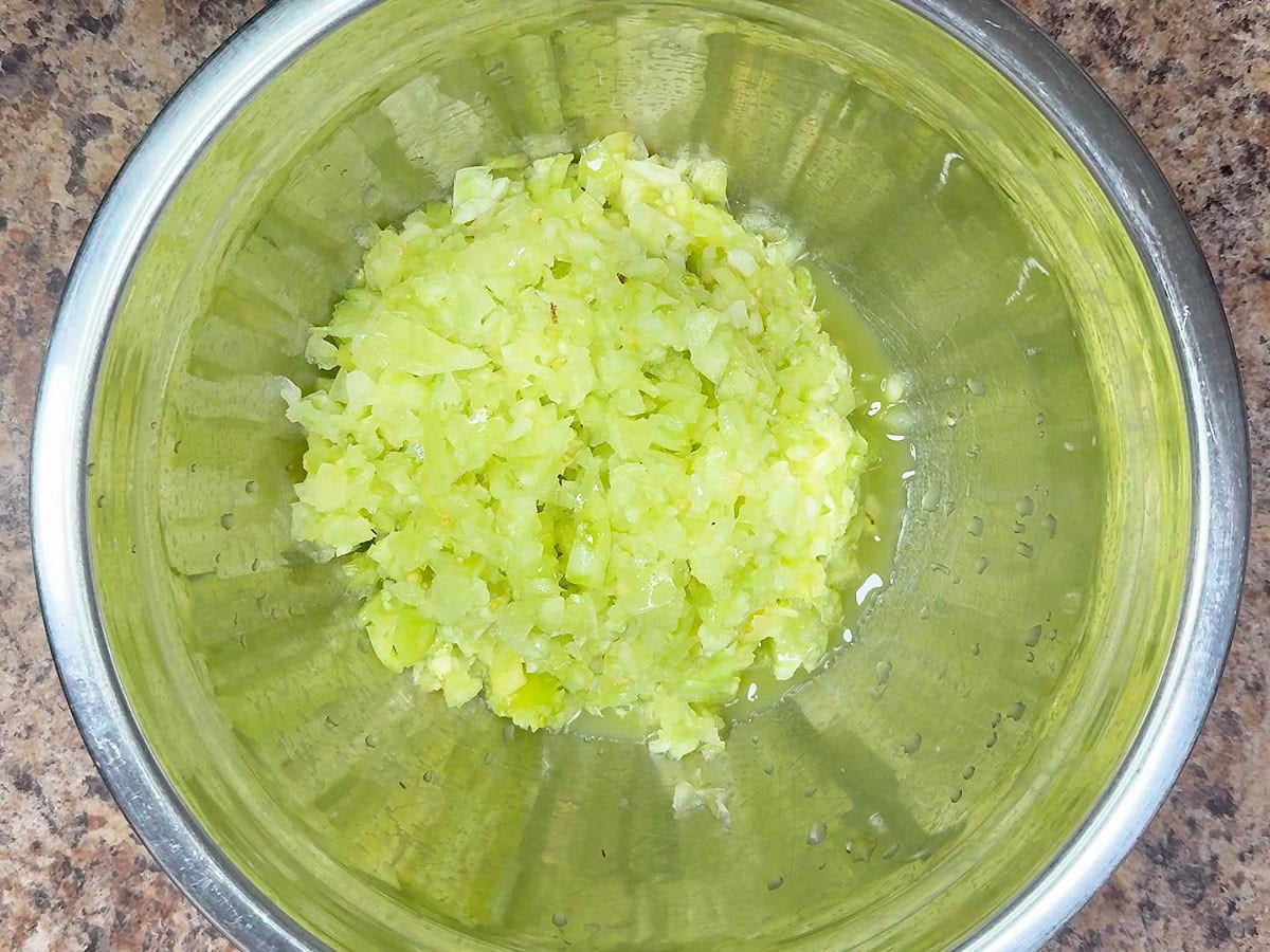 Diced green tomatoes in a metal mixing bowl.