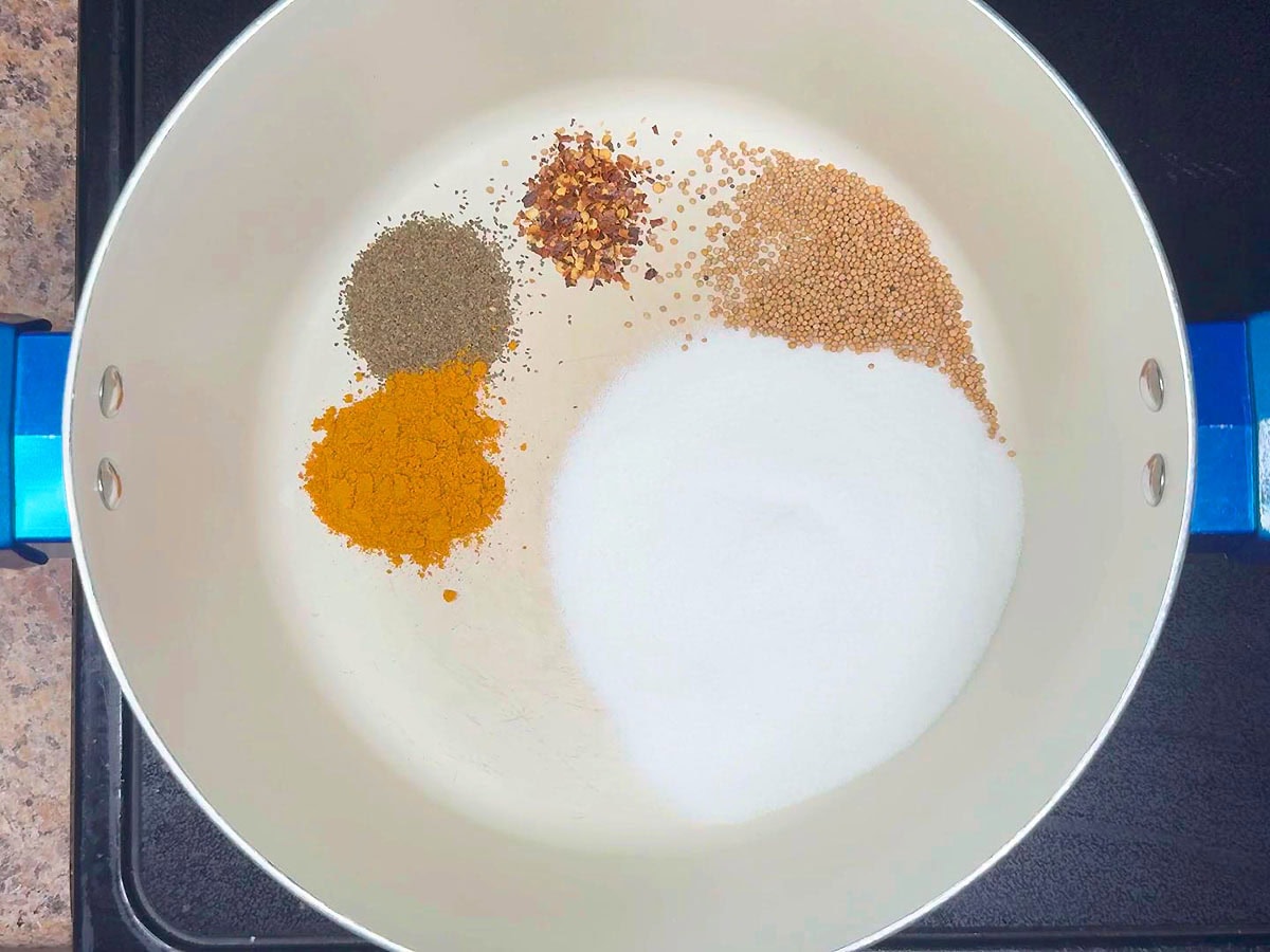 Tumeric added to celery seed, red pepper flakes, mustard seeds, and sugar in a stockpot.