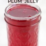Glass jelly jar of unsealed plum jelly.