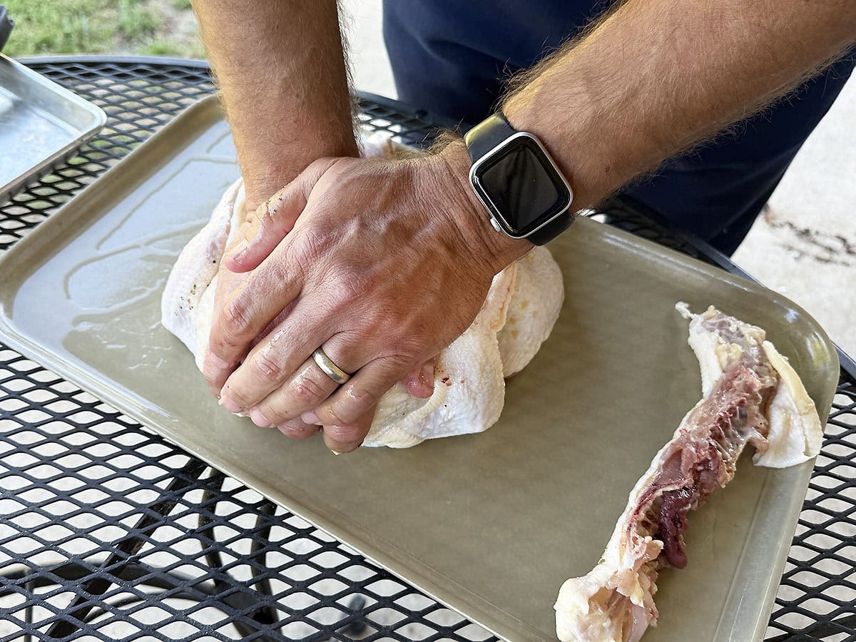 Pressing the breastbone of the chicken down to flatten it out.