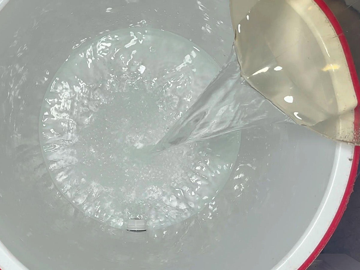 Pouring one gallon of cold water into a cooler.