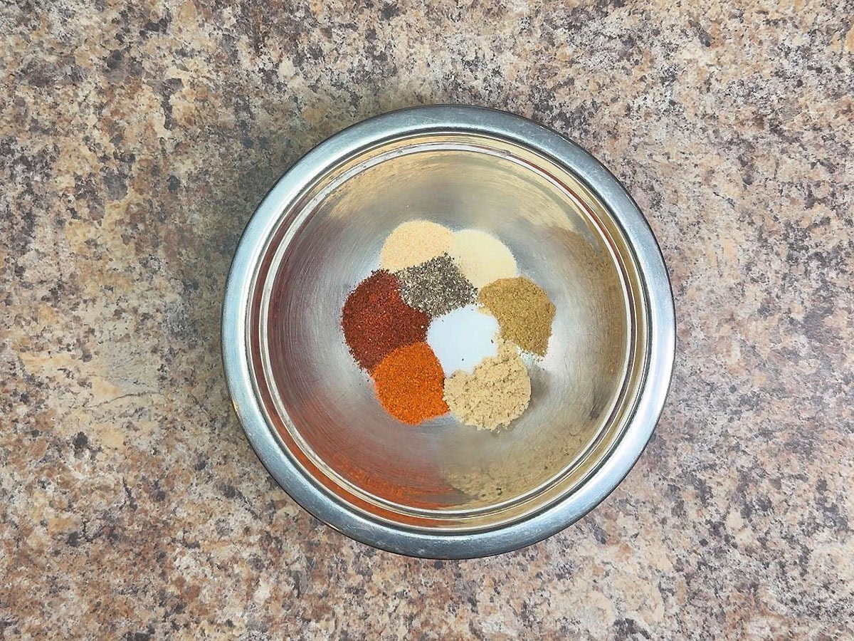 Chili powder, paprika, garlic powder, onion powder, cumin, brown sugar, salt, and black pepper in a small mixing bowl.