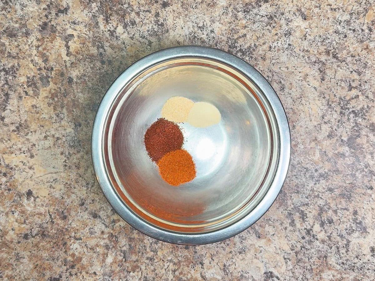 Chili powder, paprika, garlic powder, and onion powder in a small mixing bowl.
