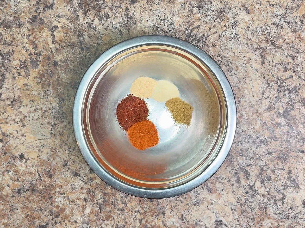 Chili powder, paprika, garlic powder, onion powder, and cumin in a small mixing bowl.